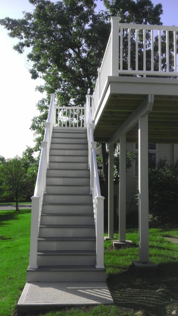 White staircase leading to an elevated porch on a sunny day.