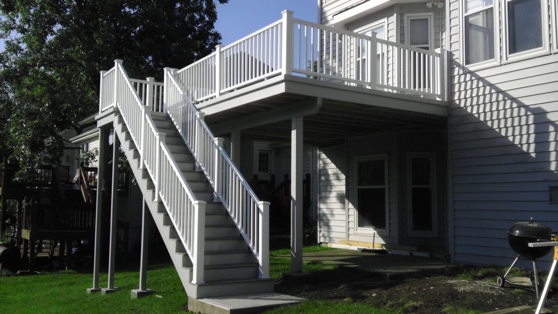 White exterior staircase leading to a deck on a house.