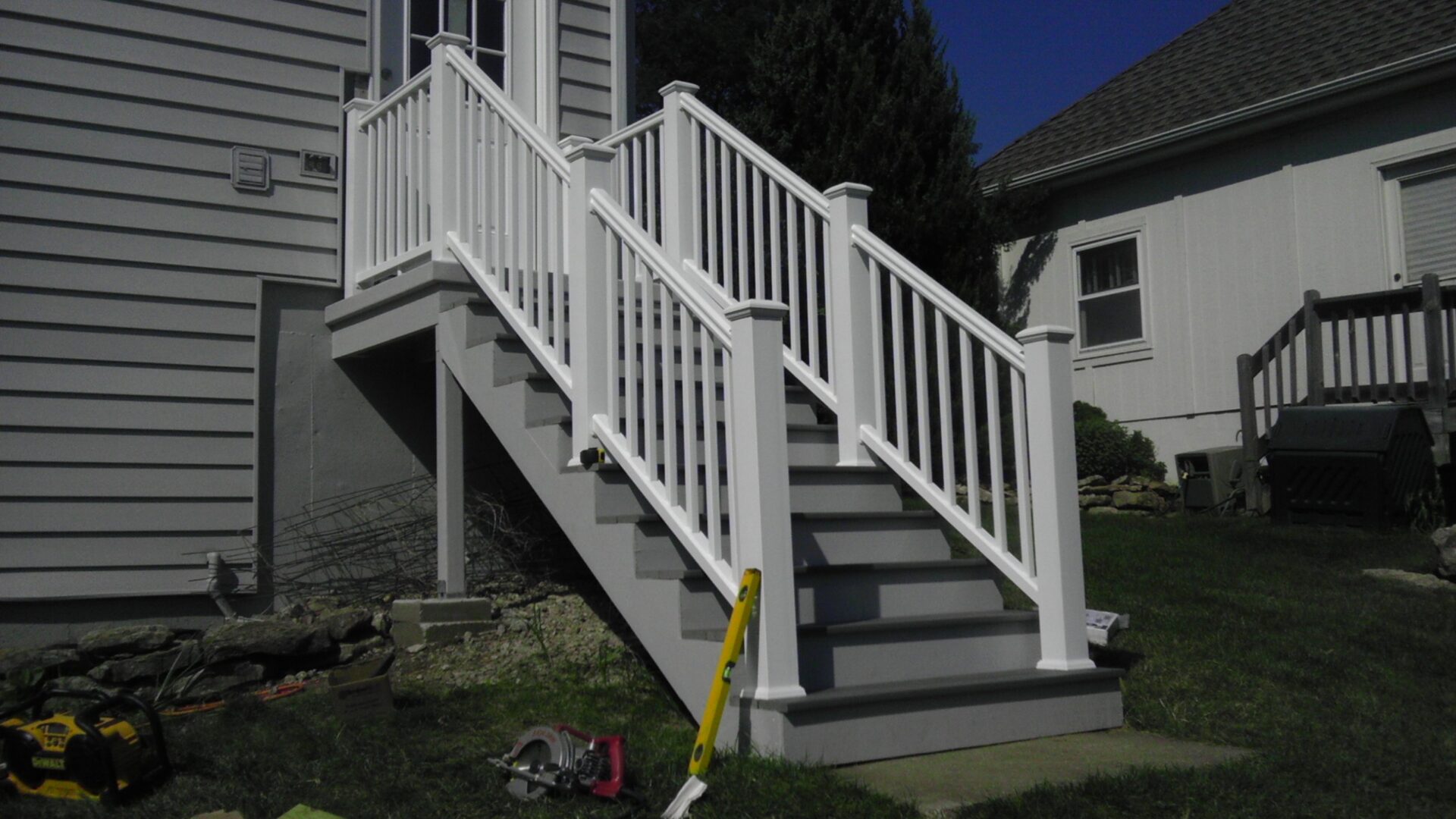 Exterior staircase with white railings and gray steps leading to a porch.