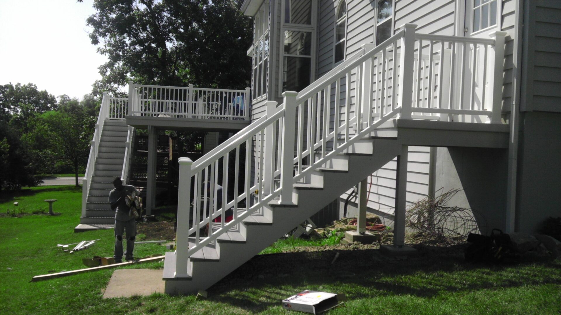 White outdoor staircase attached to a house with a deck above.