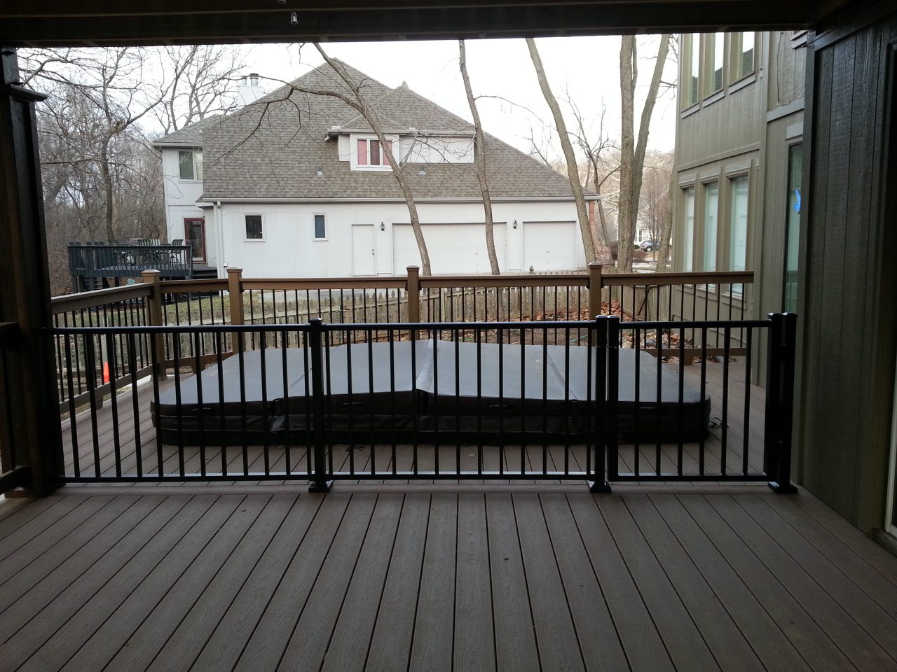A wooden deck with a railing and a covered pool in the background.