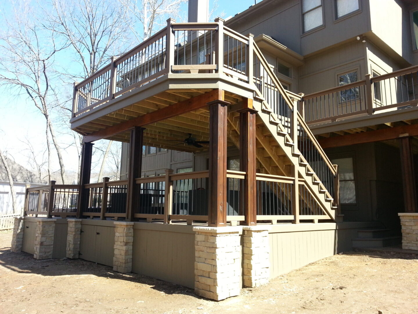 Wooden deck with stairs and railing attached to a house.
