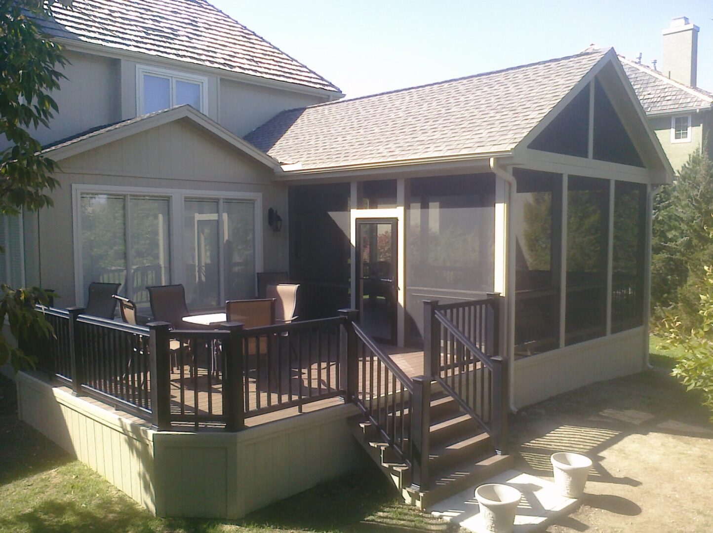 A house with a screened porch and wooden deck with stairs.