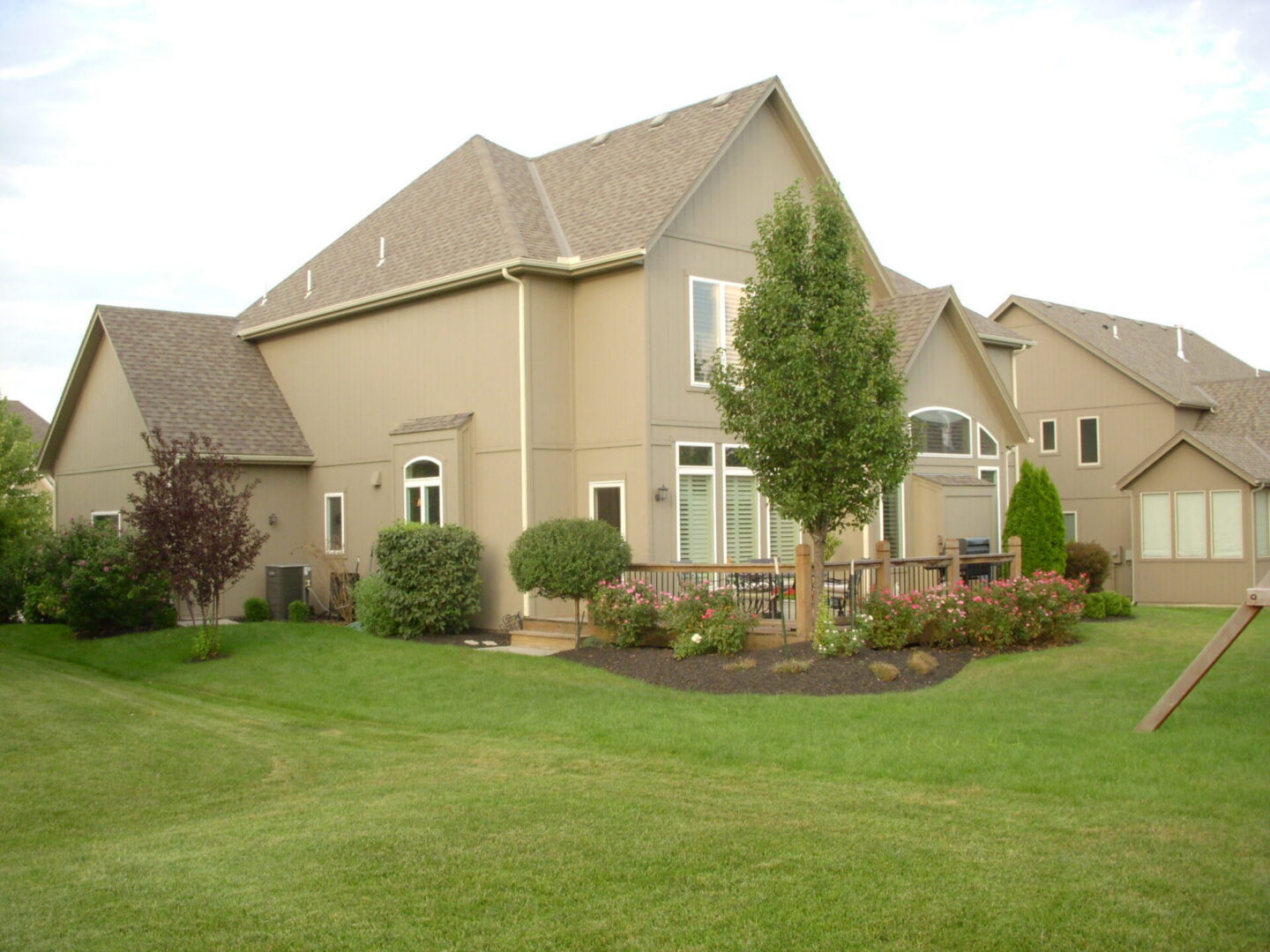 Large suburban beige house with landscaped backyard