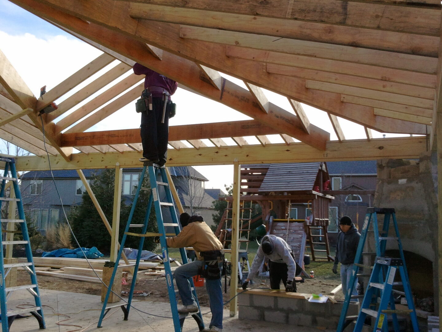 Workers building wooden roof frame in backyard