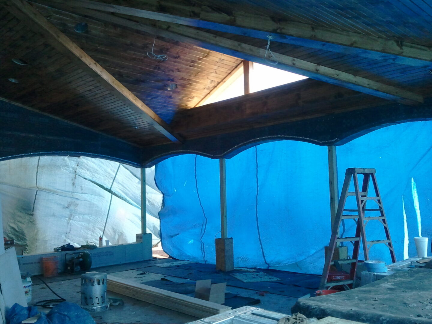 Interior renovation with blue tarp and ladder
