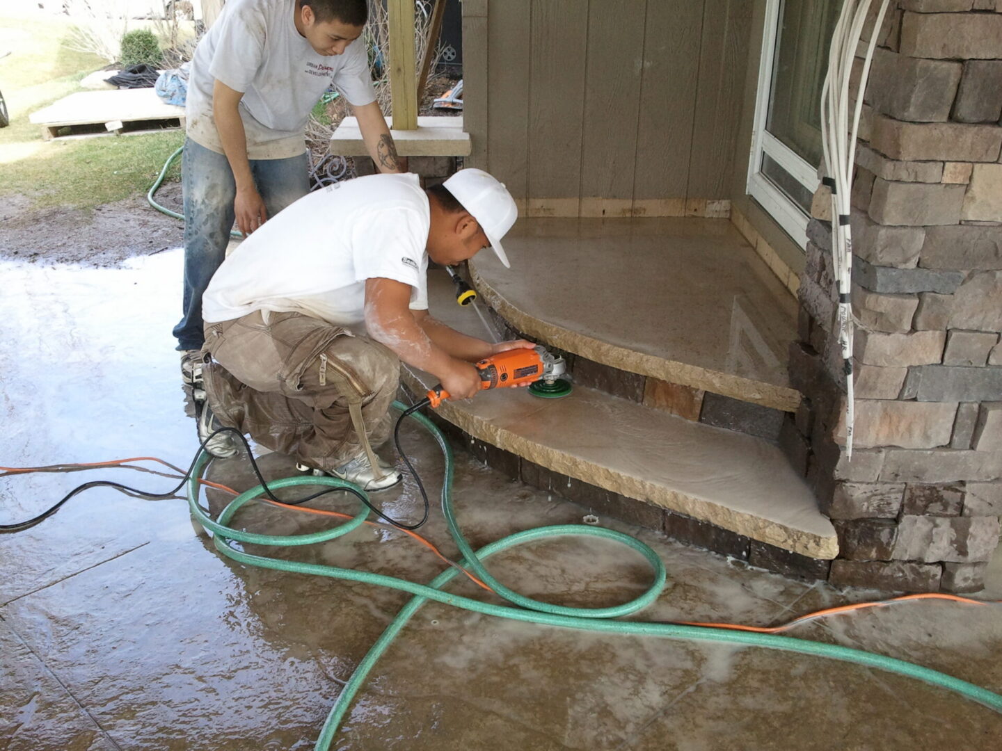 Two workers polishing concrete porch steps