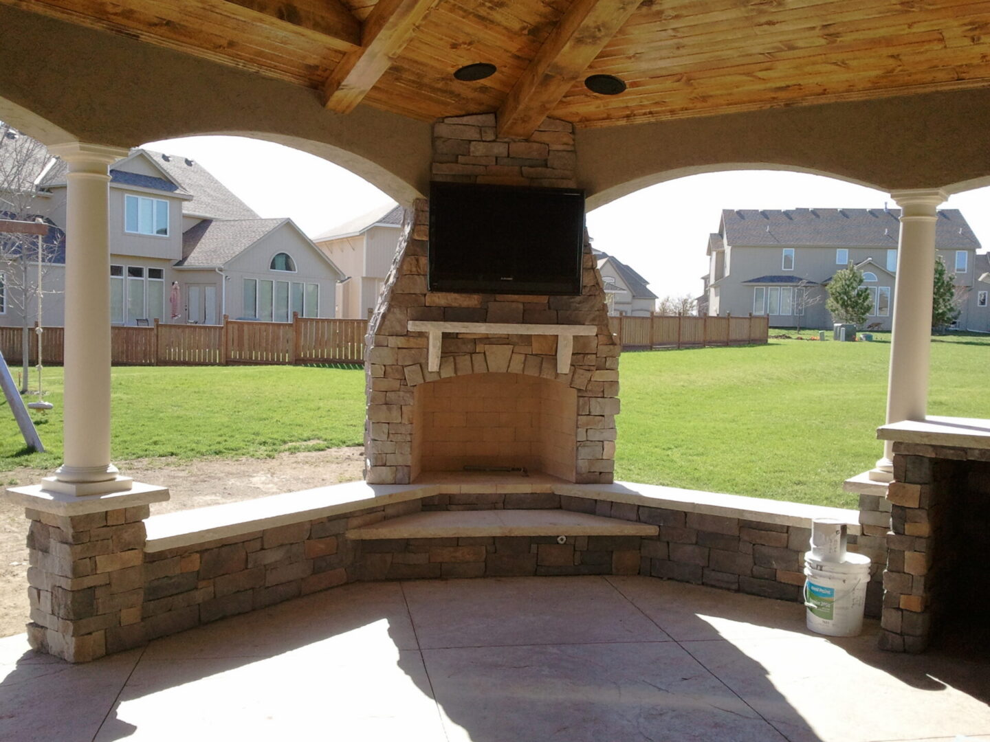 Covered patio with stone fireplace and TV