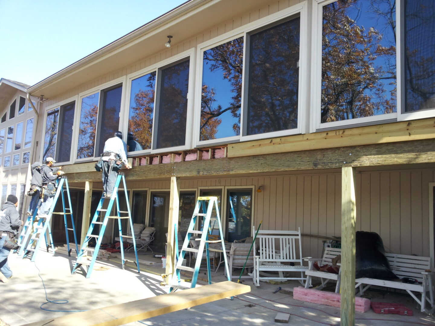 Construction crew replacing porch beam under windows
