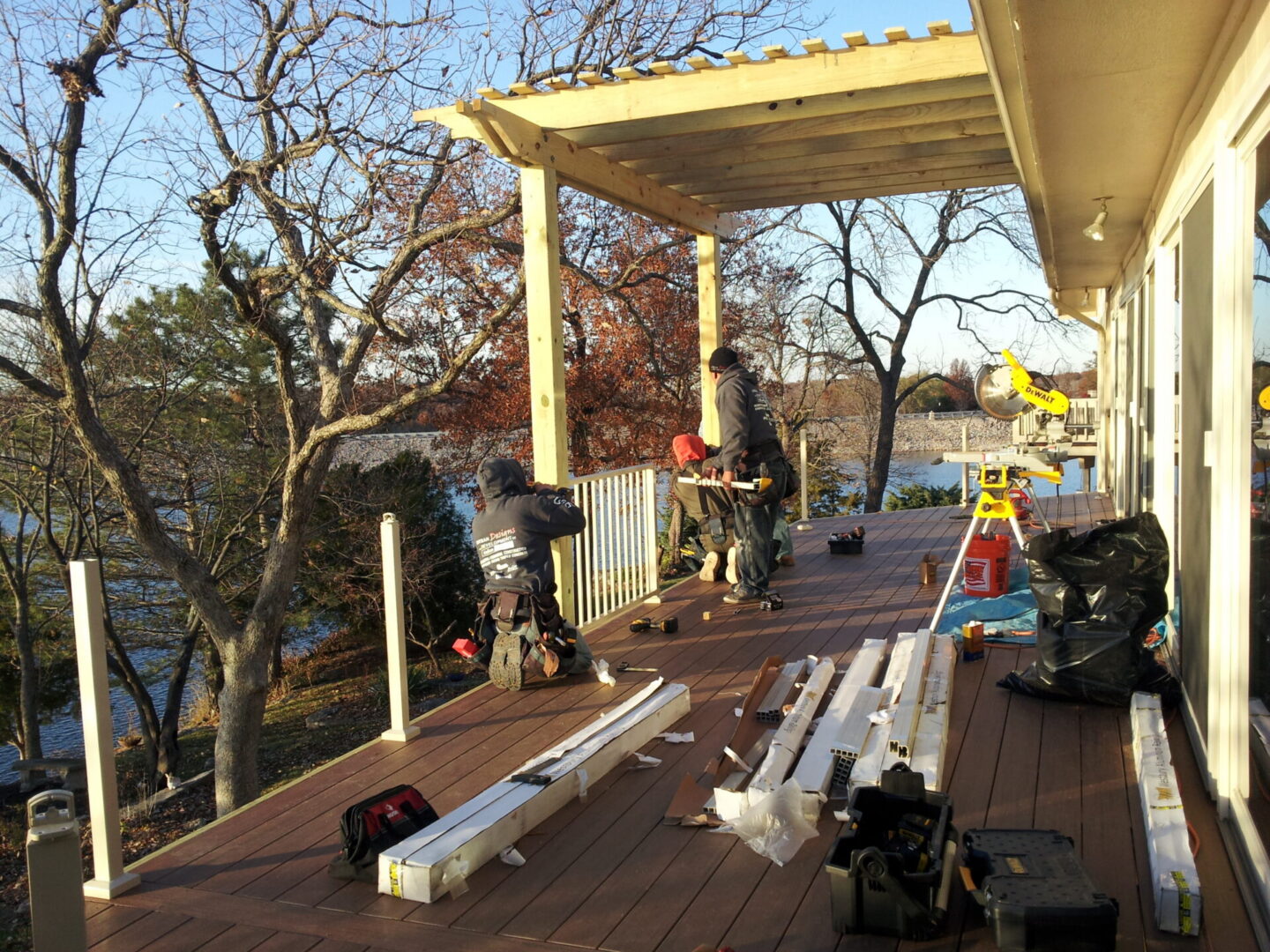 Workers building deck pergola overlooking lake