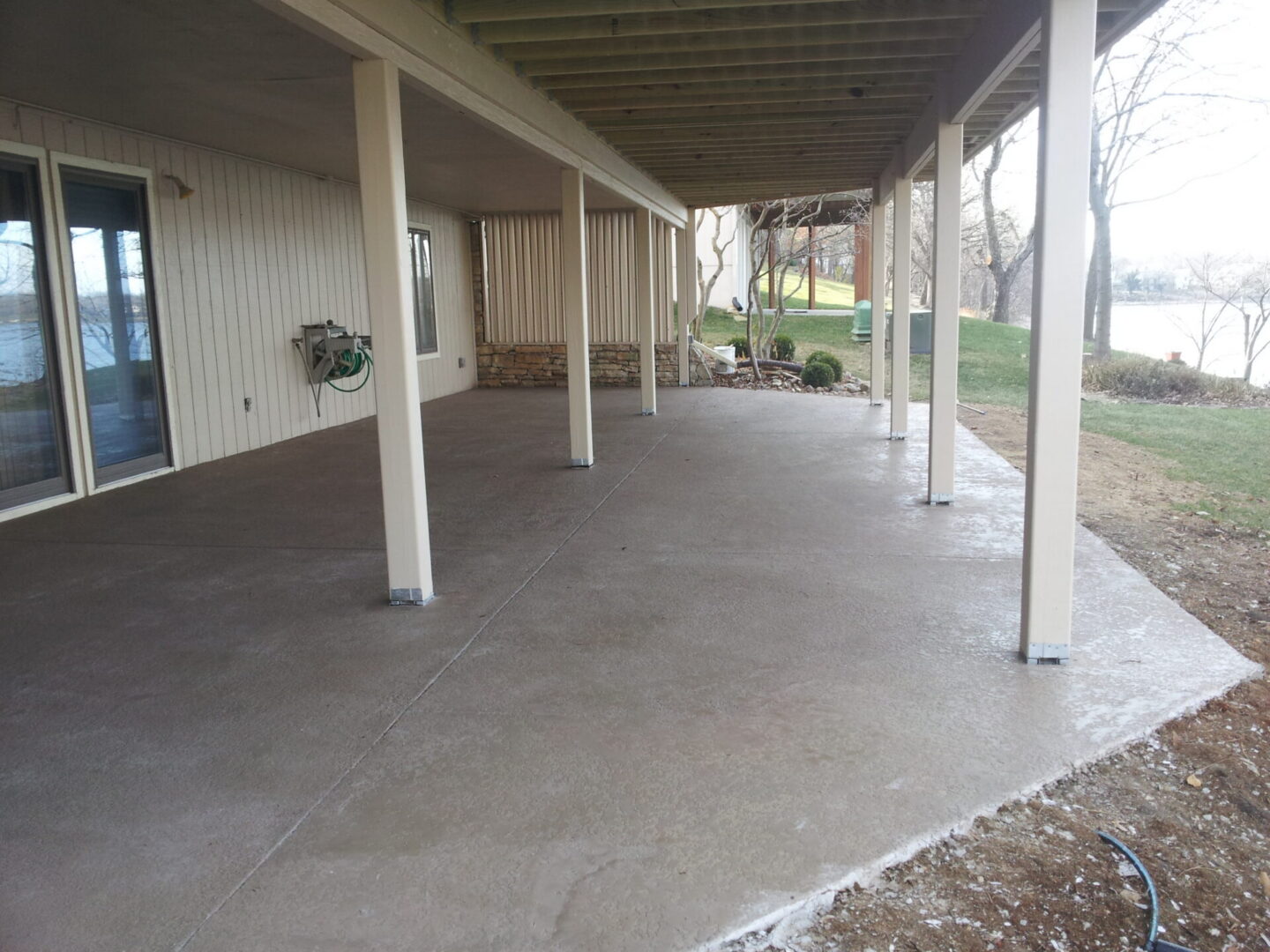 Covered concrete patio under deck with columns