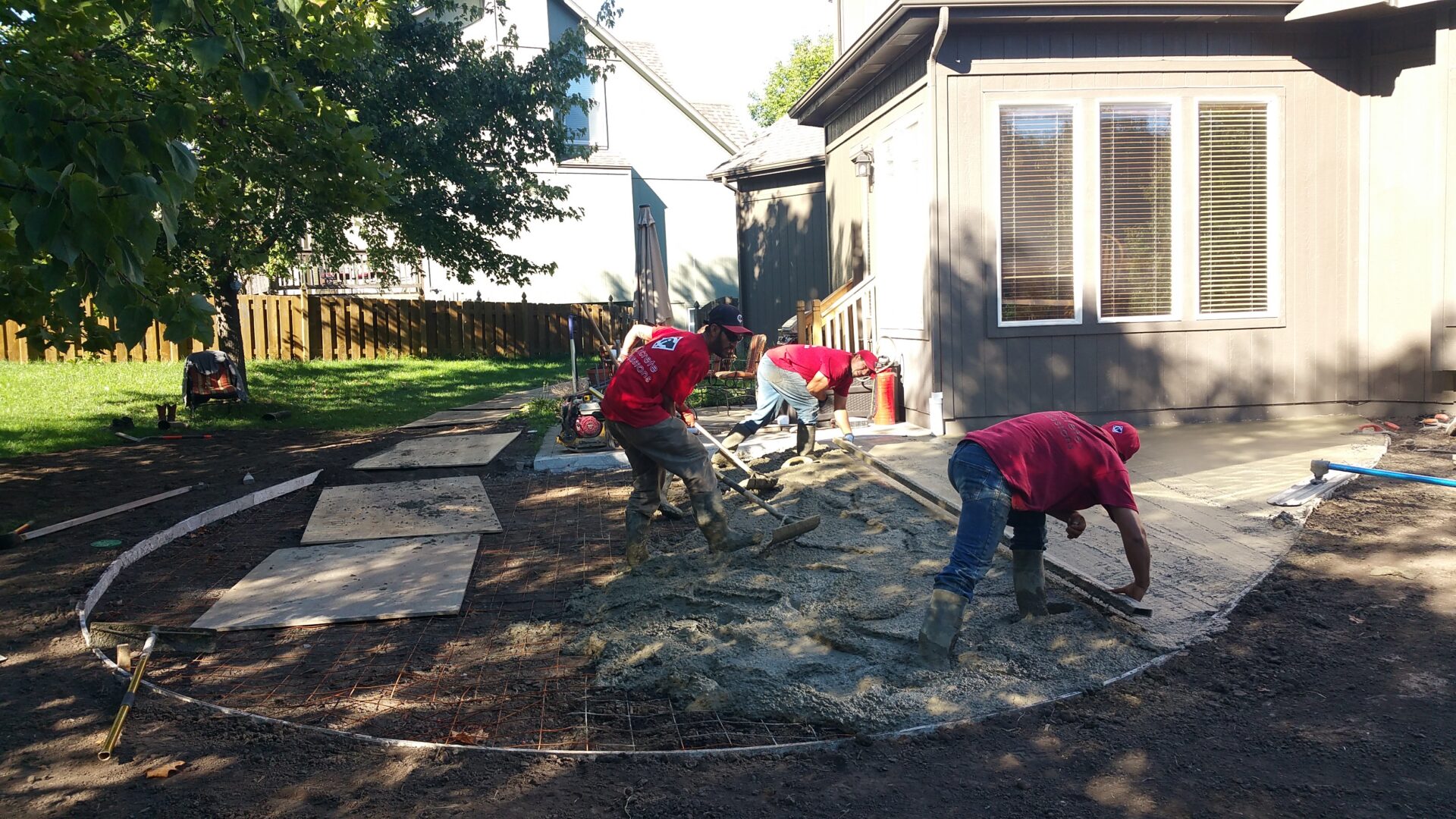 Workers pouring concrete for backyard patio