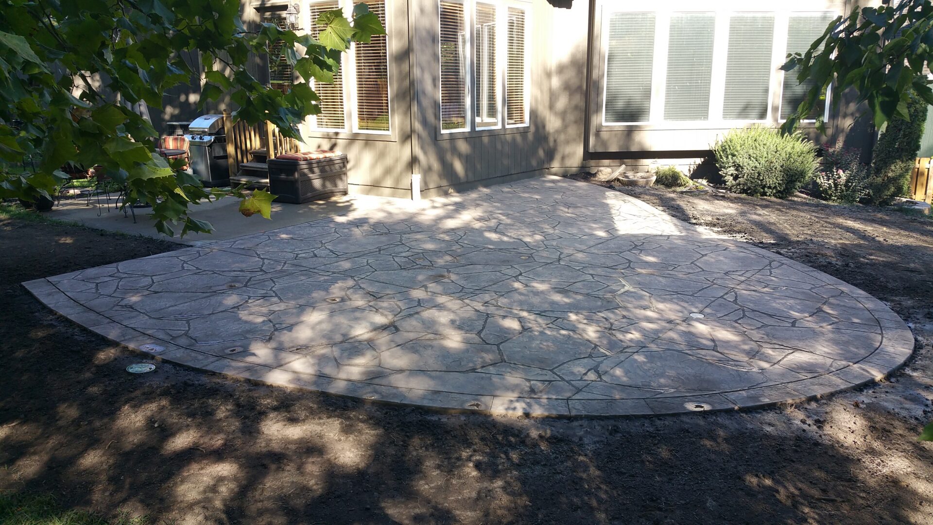 Stamped concrete backyard patio with curved edge