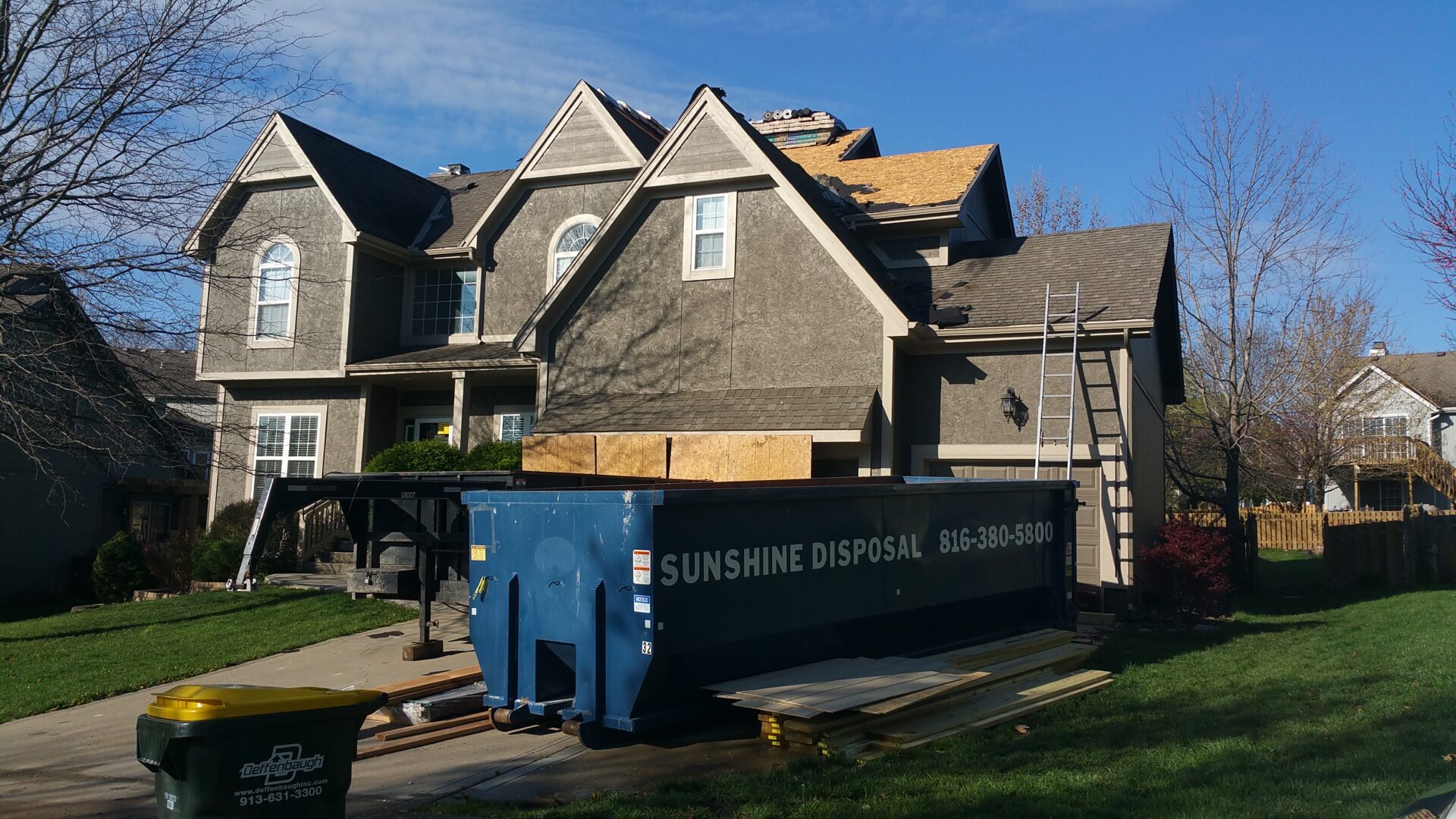 House undergoing roof replacement with dumpster