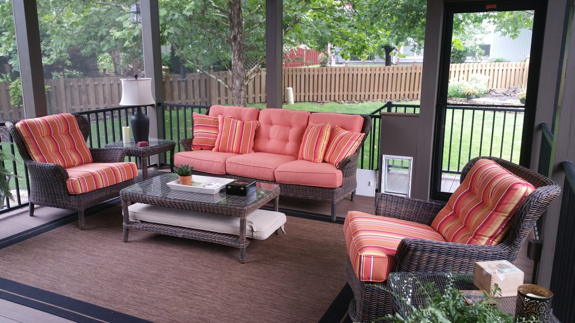 Screened porch with wicker seating and coral cushions