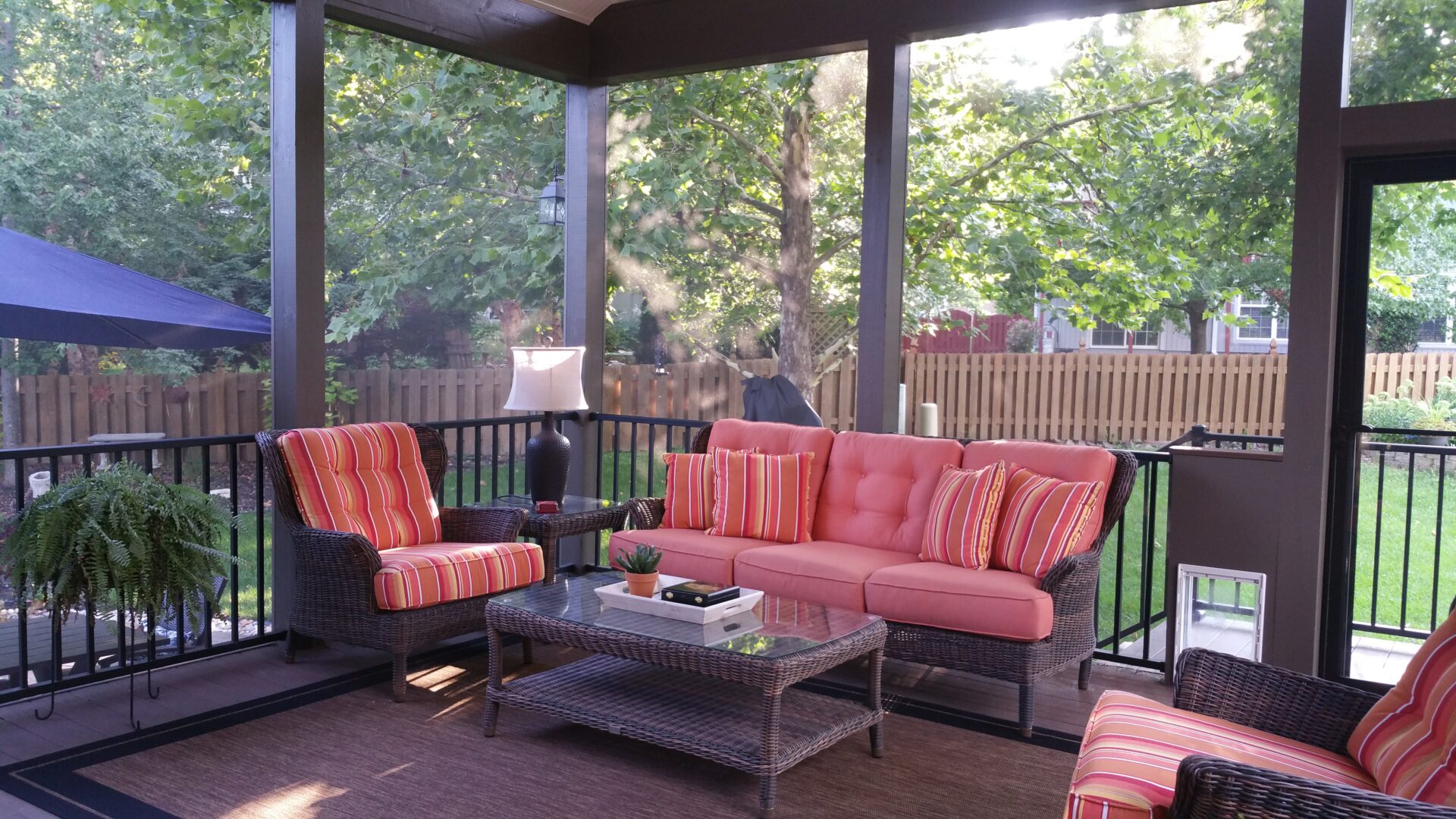 Screened porch with coral cushioned wicker furniture