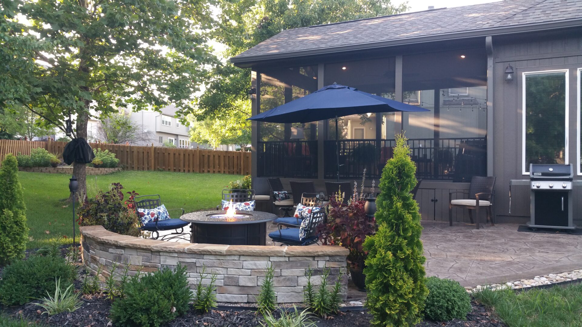 Backyard patio with stone fire pit and umbrella