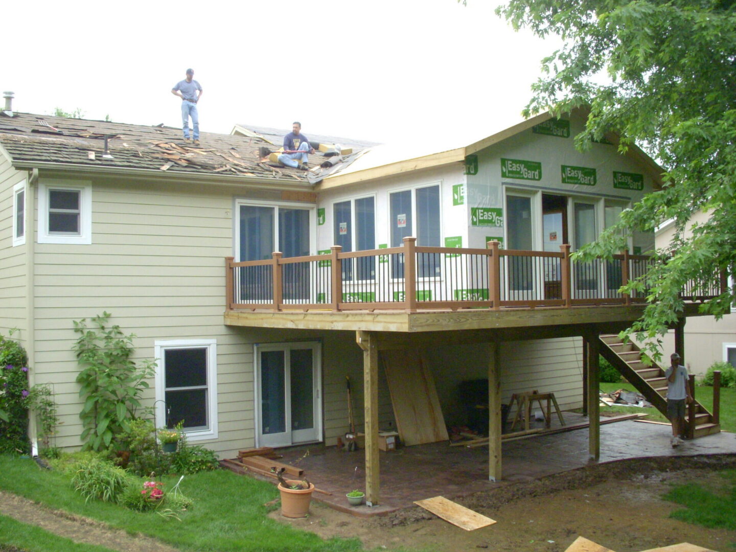 Roof repair workers on house with deck