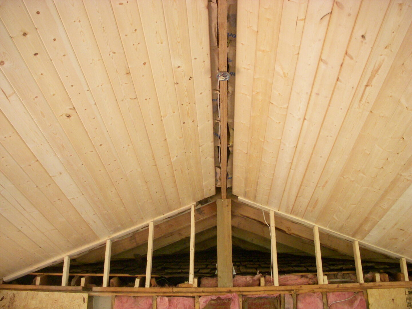 Wooden attic ceiling with exposed beams and studs