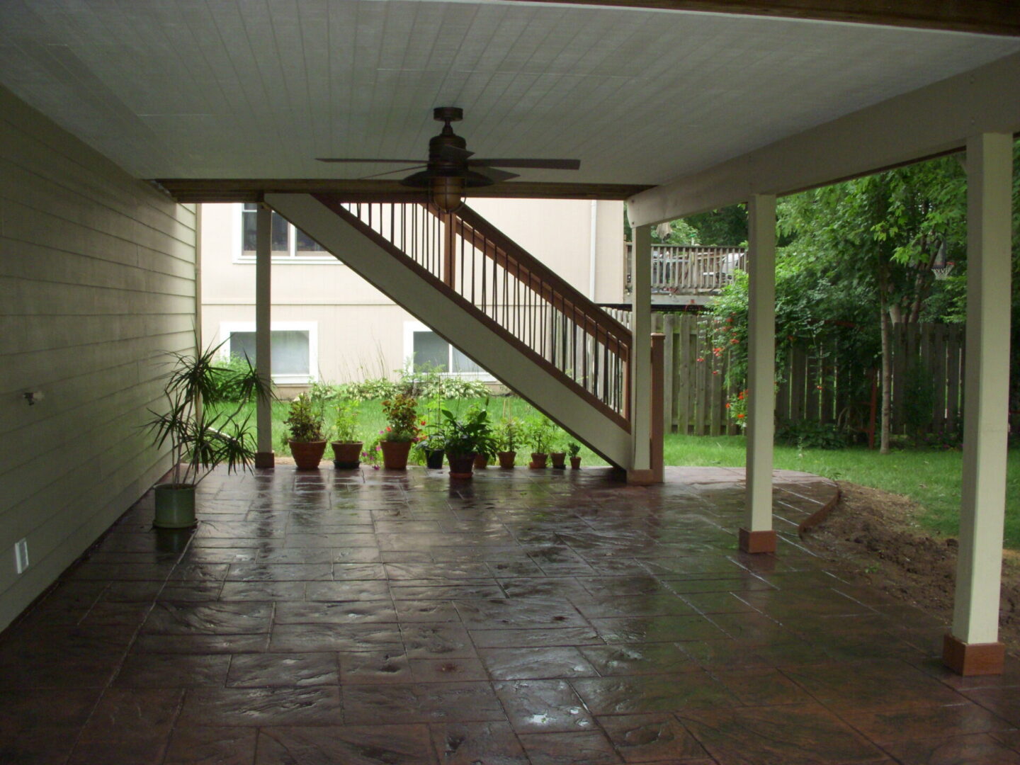 Covered patio under staircase with potted plants
