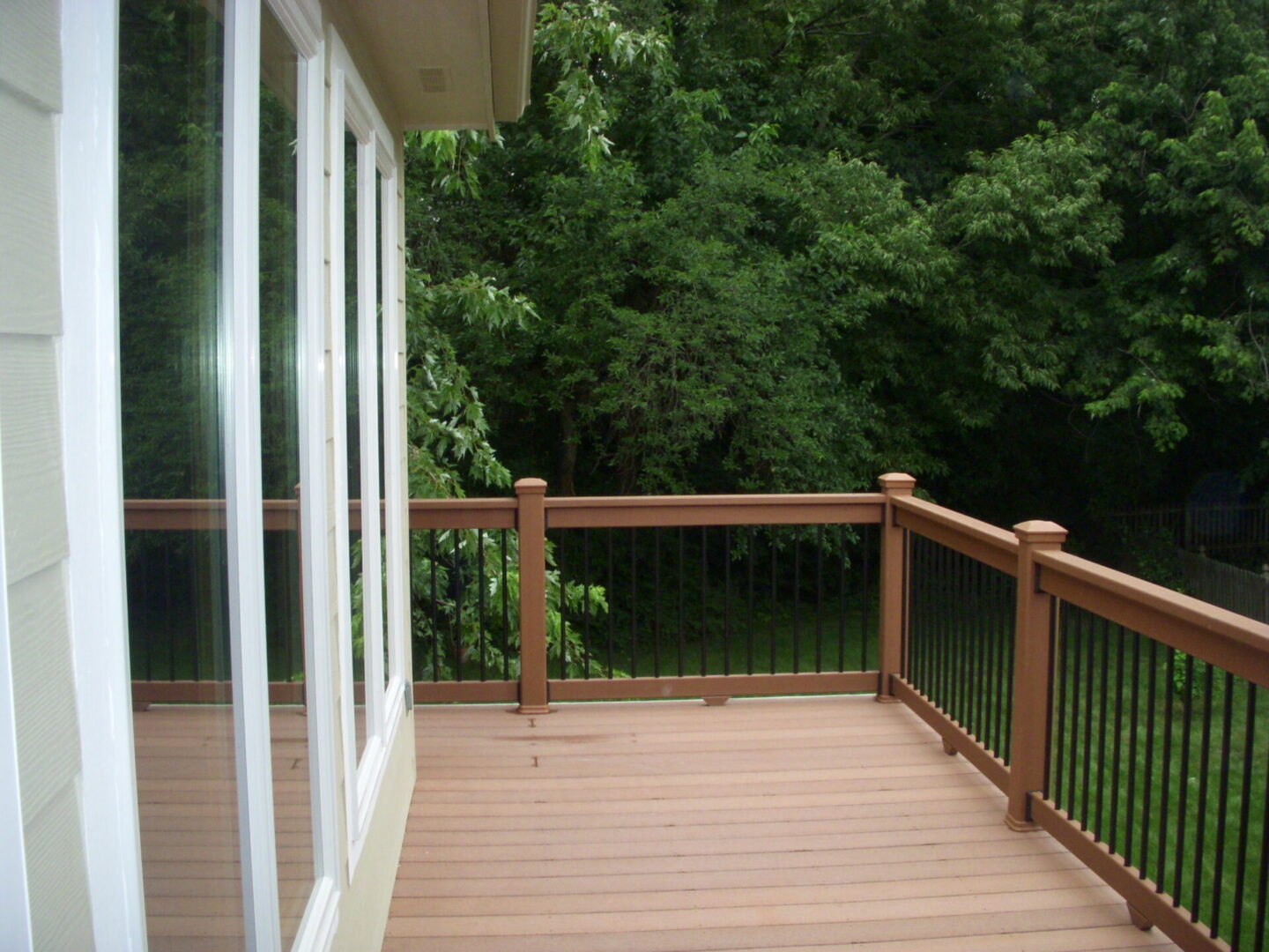 Wooden backyard deck with railing and trees