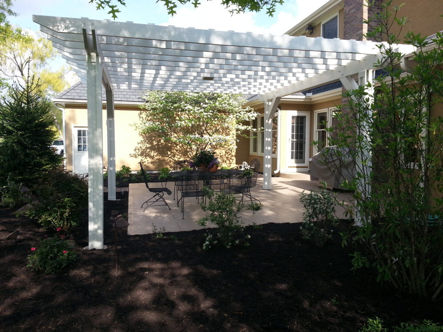 Backyard patio with white pergola and table